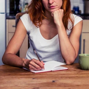 Person sitting at a table writing down a list of their skills and strengths