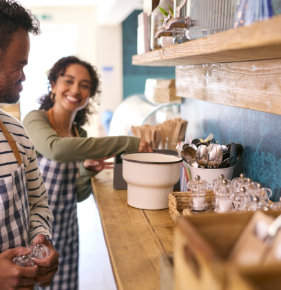 Woman And Man With Down Syndrome Working In Coffee Shop Or Restaurant