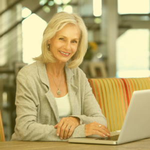 woman smiling in front of laptop looking like she has just achieved something positive