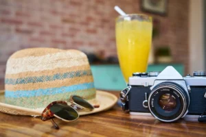 Sunglasses, Hat And A Camera Sitting On A Table