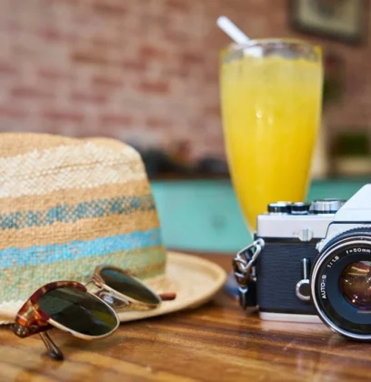 Sunglasses, Hat And A Camera Sitting On A Table