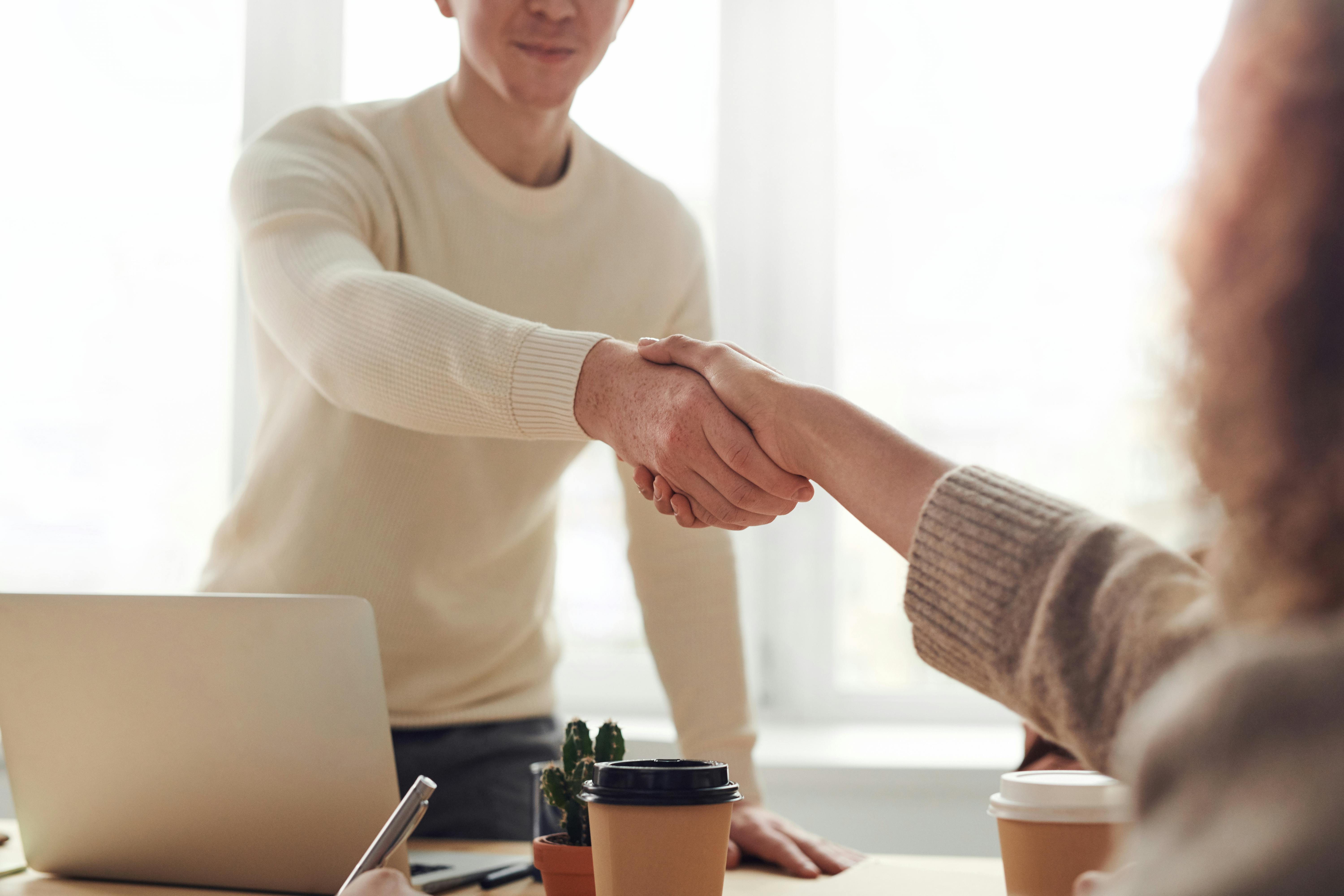 Man Shaking A Womans Hand Across A Table During An Interview