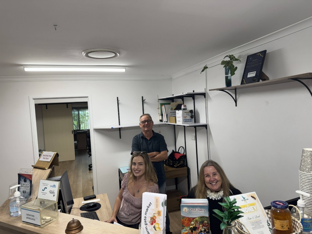 staff behind receiption at Maroochy Neighbourhood Centre smiling at the camera