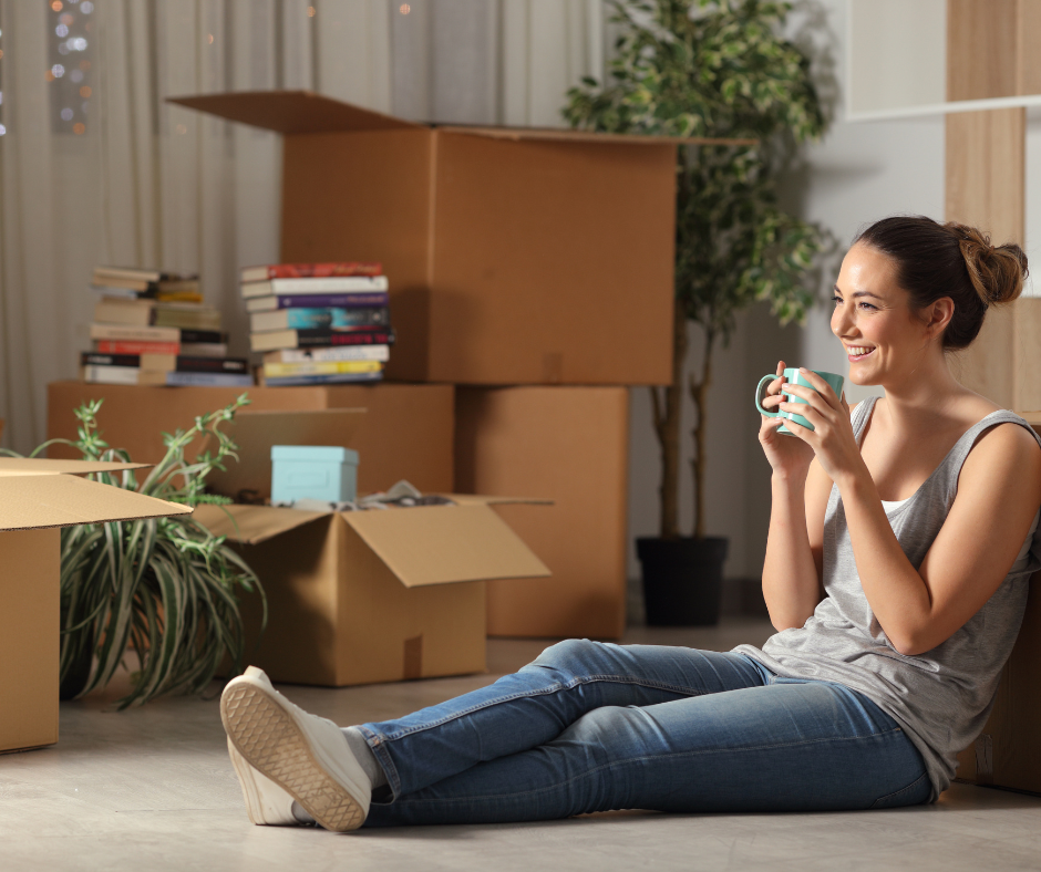 Person sitting amongst moving boxes resting and enjoying coffee